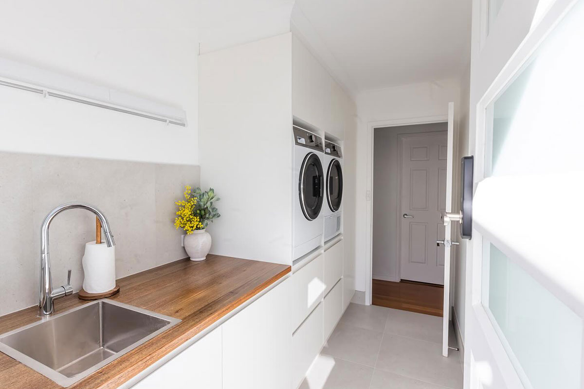 Stylish laundry interior with cabinetry and appliances